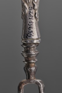 Fork. Two-pronged steel fork with a silver handle shaped as a full-plastic female herm, decorated