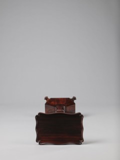 Pedestal table with a rectangular top with a wavy-cut edge and a low wooden gallery, supported by