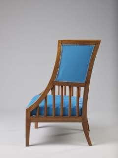 Armchair Berzera with a slender backrest and sides equal in height, arching upwards and forming