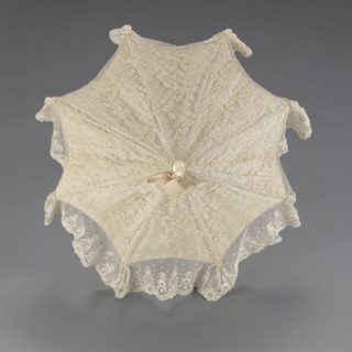 Women's umbrella made of white lace. Its canopy is trimmed with cream silk at the bottom, which