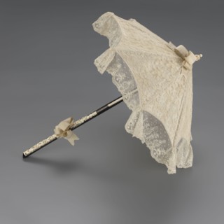 Women's umbrella made of white lace. Its canopy is trimmed with cream silk at the bottom, which