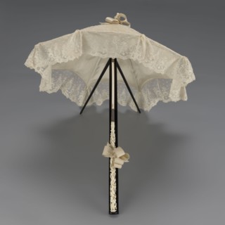 Women's umbrella made of white lace. Its canopy is trimmed with cream silk at the bottom, which