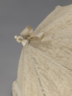 Women's umbrella made of white lace. Its canopy is trimmed with cream silk at the bottom, which