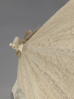 Women's umbrella made of white lace. Its canopy is trimmed with cream silk at the bottom, which