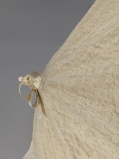 Women's umbrella made of white lace. Its canopy is trimmed with cream silk at the bottom, which