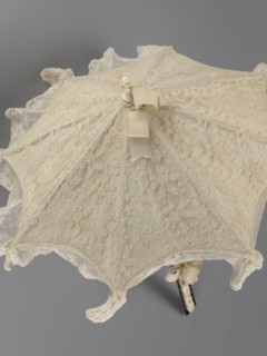 Women's umbrella made of white lace. Its canopy is trimmed with cream silk at the bottom, which