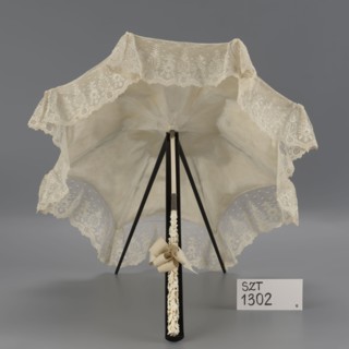 Women's umbrella made of white lace. Its canopy is trimmed with cream silk at the bottom, which