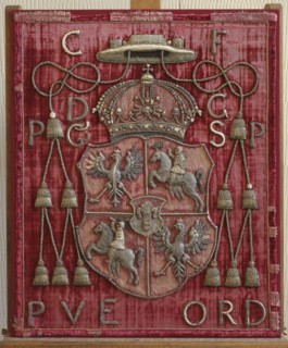 Back of a throne or bishop's chair made of red velvet with an applied coat of arms of the