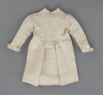 Children's dress made of cream satin. Long, fitted at the top, slightly flared at the bottom.