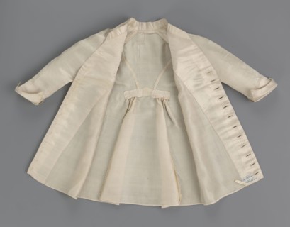 Children's dress made of cream satin. Long, fitted at the top, slightly flared at the bottom.