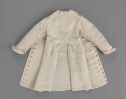 Children's dress made of cream satin. Long, fitted at the top, slightly flared at the bottom.