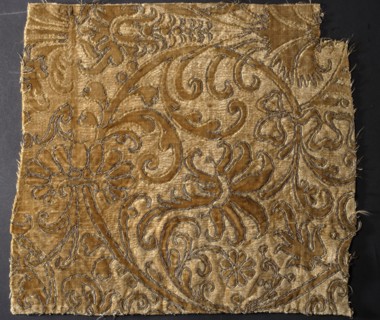 Fragment of ochre-colored sheared velvet with a raised arabesque pattern bordered with embroidery.