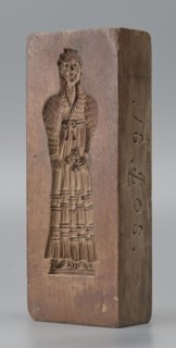 Double-sided gingerbread mould. Side A: figure of a lady in a decorative, pleated early