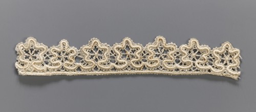 Lace fragment, needle-stitched lace, upper edge straight, lower edge serrated to match the motifs.