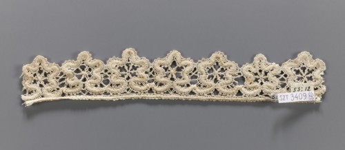 Lace fragment, needle-stitched lace, upper edge straight, lower edge serrated to match the motifs.