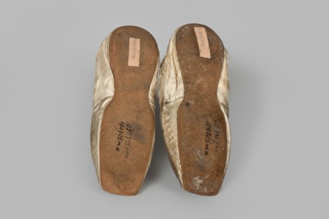 Flat women's slippers of white satin, top edge finished with ribbon. Flat-cut toes, symmetrical