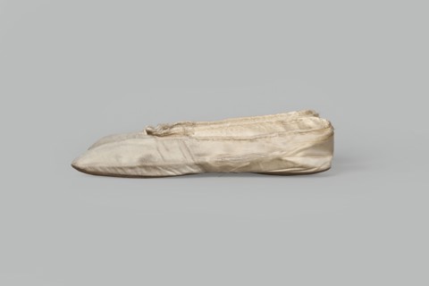 Flat women's slippers of white satin with top edge finished with ribbon. Flat-cut toes, symmetrical