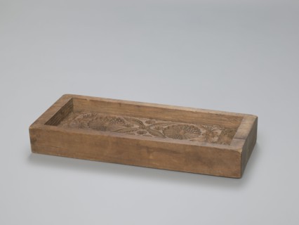 One-sided gingerbread form with the image of a rectangular floral and plant ornament. One-sided