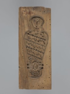 Double-sided gingerbread form. Obverse: female figure in a hat and a long patterned dress; reverse: