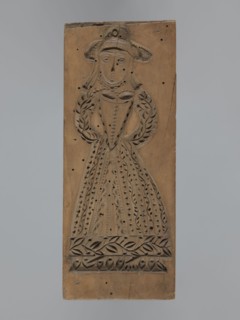 Double-sided gingerbread form. Obverse: female figure in a hat and long patterned dress; Reverse: