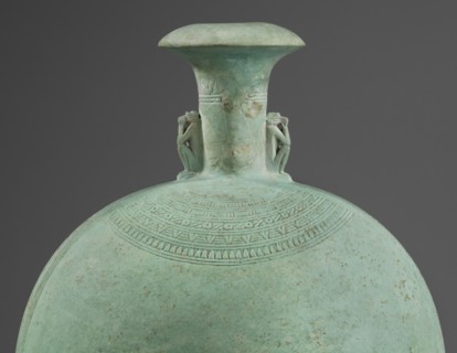 Flat round faience canteen with a narrow short neck ending in a chipped spout shaped like a papyrus