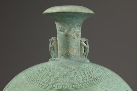 Flat round faience canteen with a narrow short neck ending in a chipped spout shaped like a papyrus