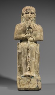 Figurine of the god Ptah sitting on a throne, on a base in the shape of the sign of Maat. He holds
