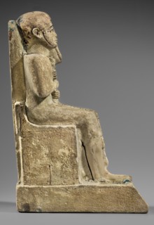 Figurine of the god Ptah sitting on a throne, on a base in the shape of the sign of Maat. He holds