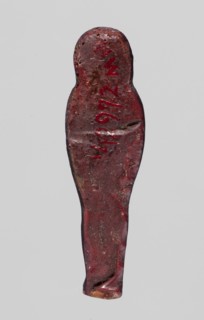 Amulet — mummy-shaped figurine, mummy-shaped figurines, grave goods; back smooth. Dark red glass.