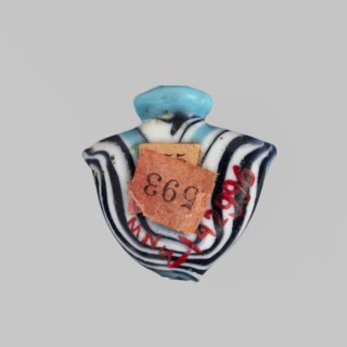 Amulet in the shape of a heart ib, made of blue glass decorated with parallel lines forming a