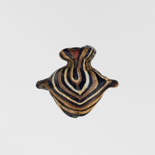 Amulet in the shape of a heart ib, made of black and brown glass decorated with parallel lines