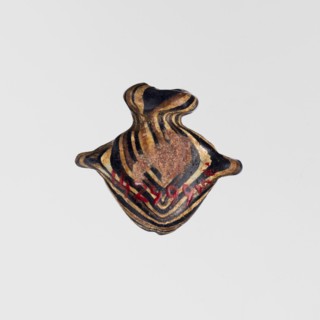 Amulet in the shape of a heart ib, made of black and brown glass decorated with parallel lines