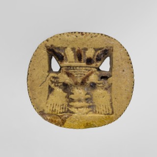 Amulet — plaque with the head of the god Bes. Amulet in the form of an oval, serrated, openwork