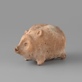 Pig-shaped rattle. A small ceramic figurine in the shape of a pig, likely a toy rattle. The animal