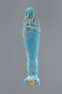Ushabti, Mummy-shaped figurine, standing on a base, back supported by a pillar/pilaster. Arms