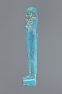 Ushabti, mummy-shaped figurine standing on a base, back supported by a pillar/pilaster. Arms