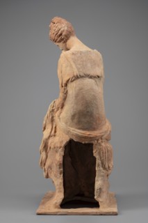Figurine of a woman sitting on a rock with a flower in her hand. Woman sitting on a rock with a