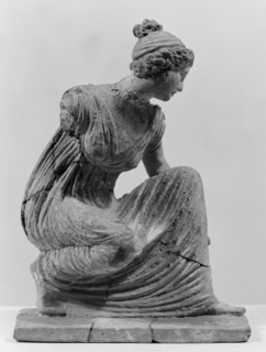 Terracotta figurine of a girl throwing dice. Figurine of a crouching girl throwing dice: the weight