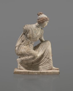 Terracotta figurine of a girl throwing dice. Figurine of a crouching girl throwing dice: weight of