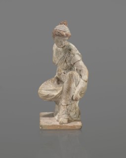 Terracotta figurine of a girl throwing dice. Figurine of a crouching girl throwing dice: weight of