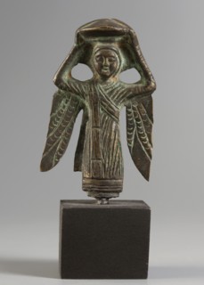 Figurine of a winged woman. Figurine depicting a woman standing frontally. Round face with clearly