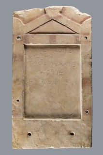 Small limestone stele with simple architectural decoration. Recessed epigraphic field surrounded by