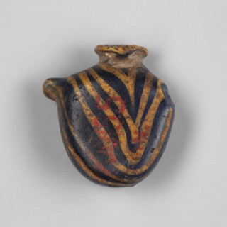 Pendant in the shape of a flattened oval vessel resembling the ib amulet. Low, narrow neck with a