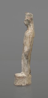 Female terracotta figurine of a standing woman, depicted frontally. Set on a small hollow,