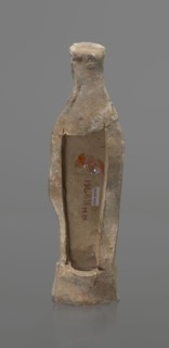 Female terracotta figurine of a standing woman, depicted frontally. Set on a small hollow