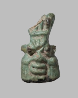 Amulet in the shape of Bes's head decorated with a crown. The grotesque face with sideburns is
