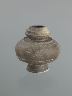 Jug with a bulging belly on a high foot. Ceramic jug decorated with plant twig motifs and raised