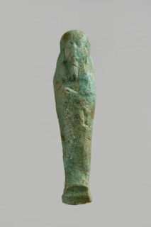 Ushabti figurine, very schematically designed. Distinct narrow beard, tools in crossed hands. Flat