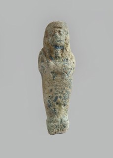 Ushabti. Carelessly made figurine with schematic facial features, in a narrow wig revealing the