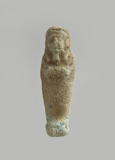 Ushabti. Carelessly made figurine with schematic facial features, in a narrow wig revealing the
